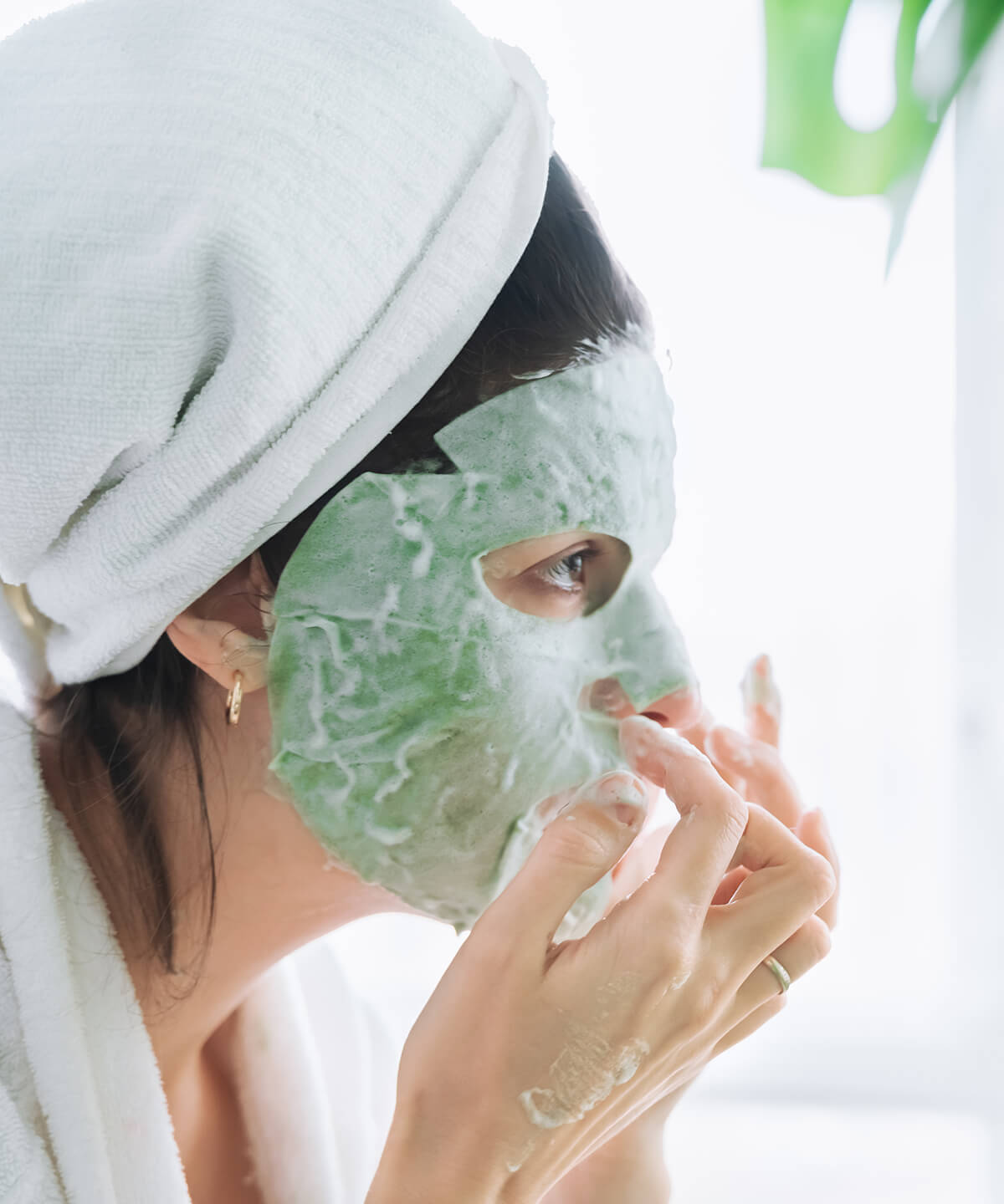 beautiful-young-woman-applies-moisturizing-green-bubble-face-mask-looking-mirror-white-bathrobetowelself-skin-careanti-age-morning-treatment-wrinkles-homeapartment-with-green-plants