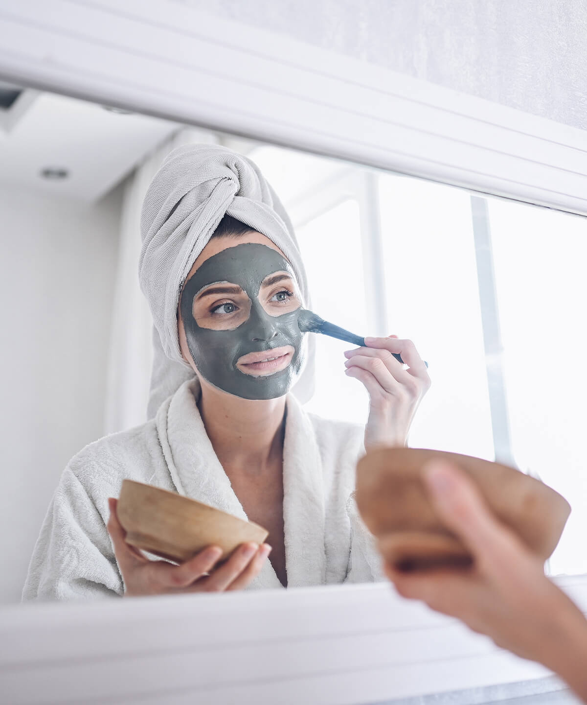 cosmetology-skin-care-face-treatment-spa-natural-beauty-concept-beautiful-smiling-woman-home-bathrobe-with-towel-applying-face-clay-mask-against-acne-rejuvenate-problem-skin