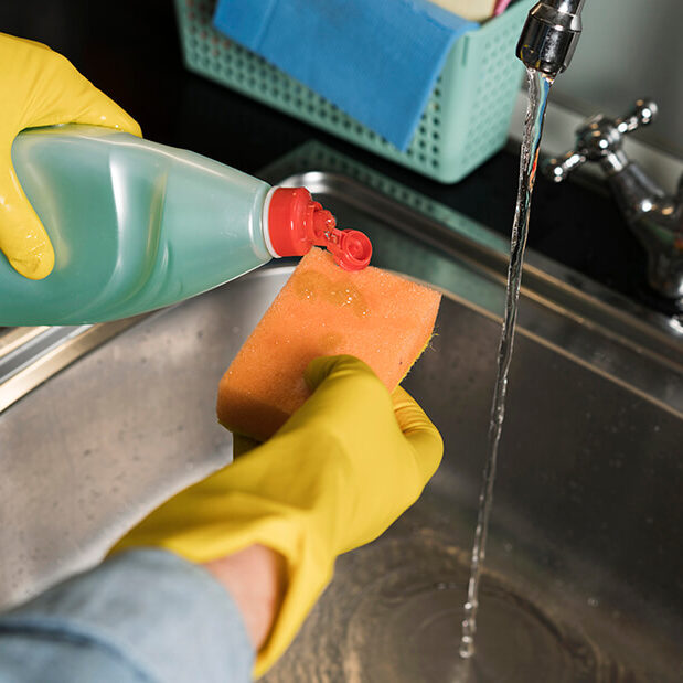 woman-with-rubber-gloves-cleaning-sink
